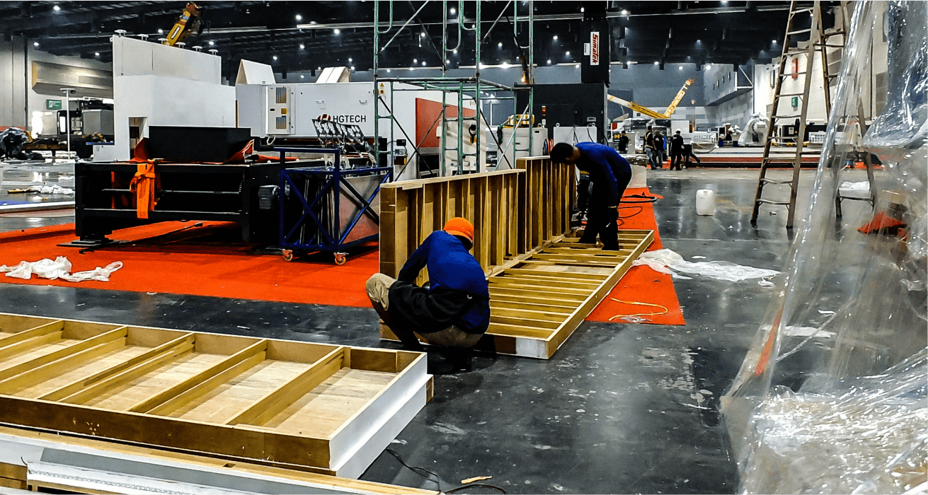 Workers assembling an exhibition booth on the show floor