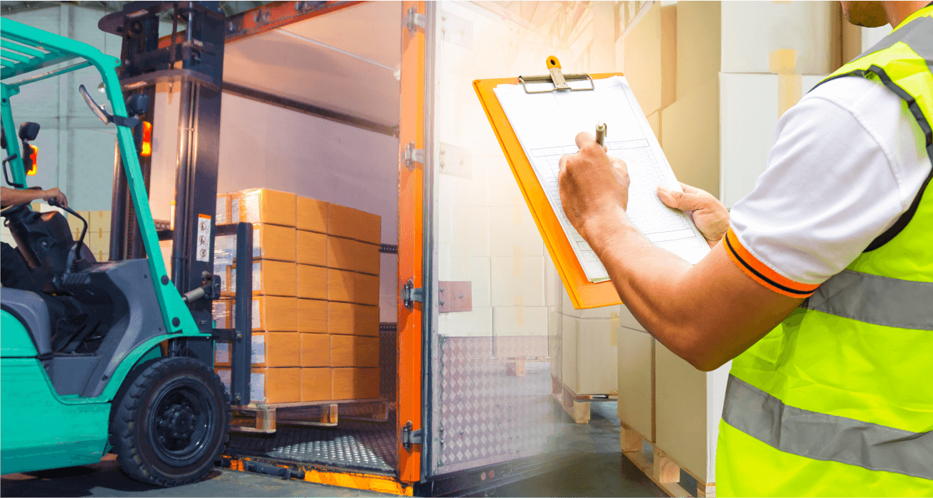 Warehouse worker checking a clipboard beside a forklift and shipping crates