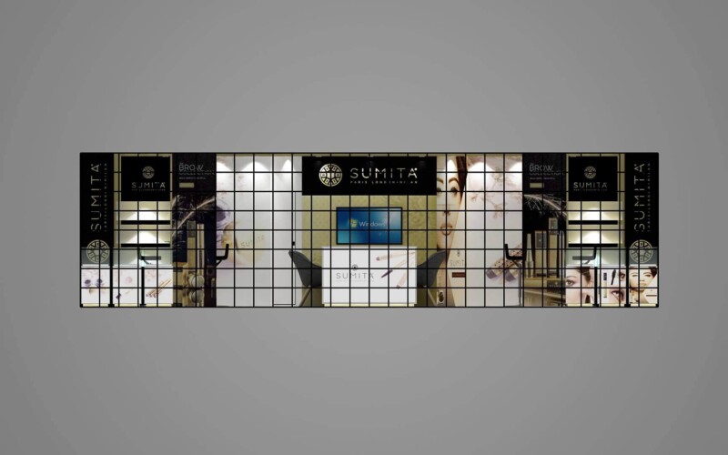 Cosmetics booth design with illuminated product shelving, large portrait graphics and a central display screen.