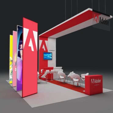 Adobe booth with a red overhead beam, tall logo panels and an open meeting area.
